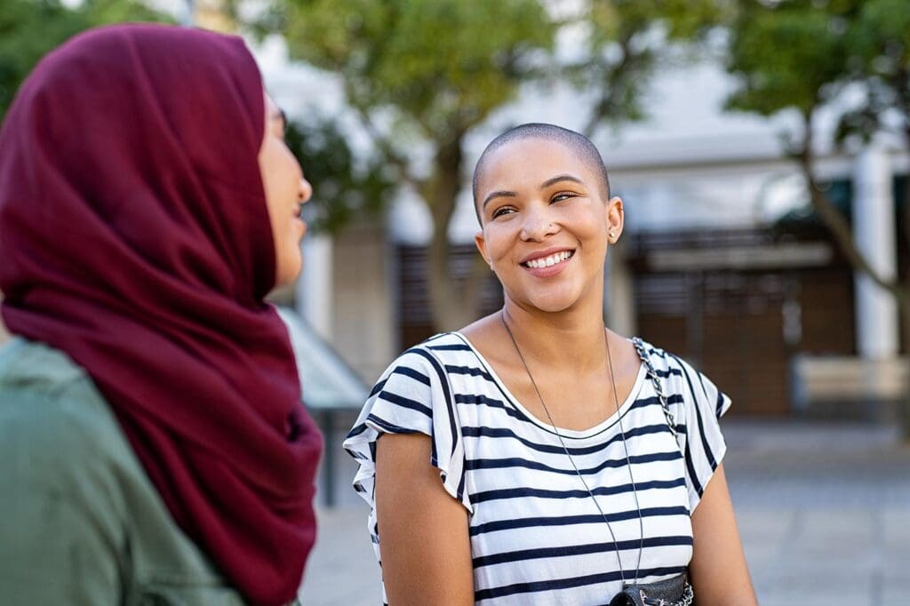 Two women with headscarves smiling together